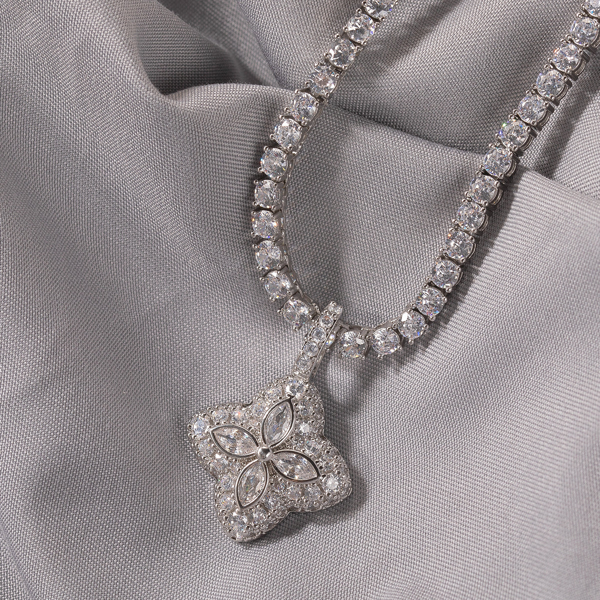 Clear-stone four-leaf clover pendant displayed on soft gray fabric