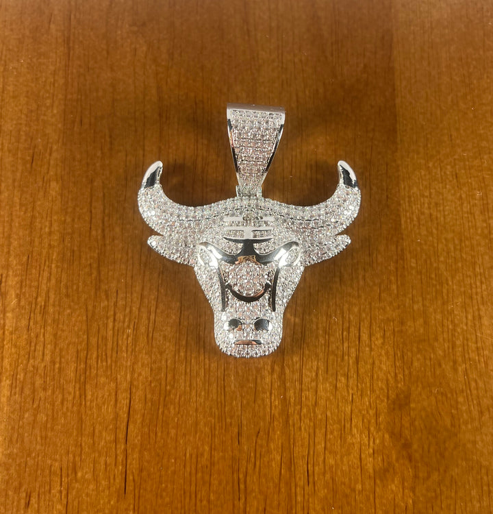 Silver-tone stone-set bull head pendant on a wood surface