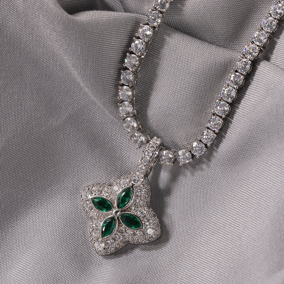 Emerald-green four-leaf clover pendant displayed on soft gray fabric