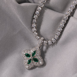 Emerald-green four-leaf clover pendant displayed on soft gray fabric
