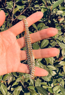 Gold iced out Cuban link bracelet with diamonds held in hand outdoors - Miles Jewellery