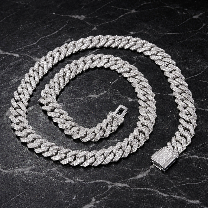 Silver-tone stone-set Cuban link chain coiled on a dark surface