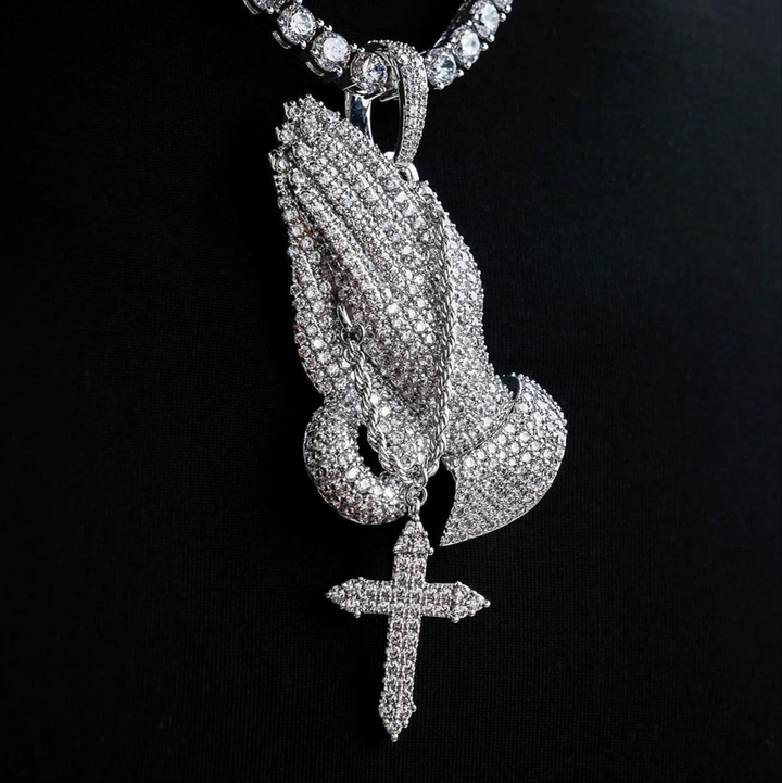 Silver-tone stone-set praying hands pendant with a hanging cross on a chain