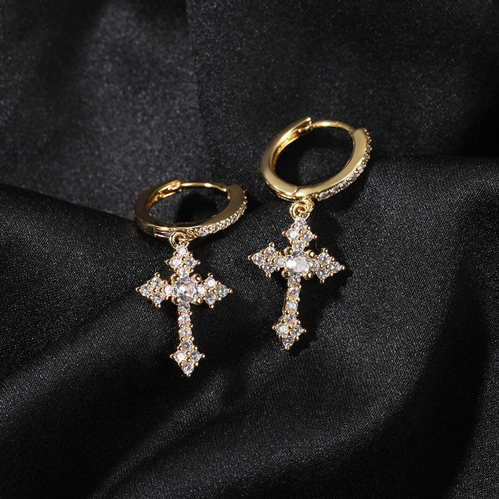 Pair of gold-tone ornate cross drop earrings on dark fabric