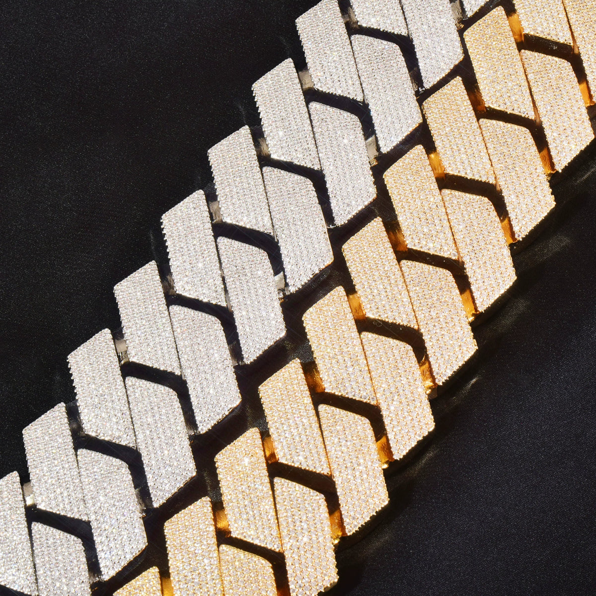 Close-up of silver-tone and gold-tone stone-set Cuban links on black