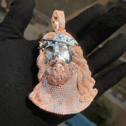 Rose-gold-tone and silver-tone Jesus portrait pendant against a black glove