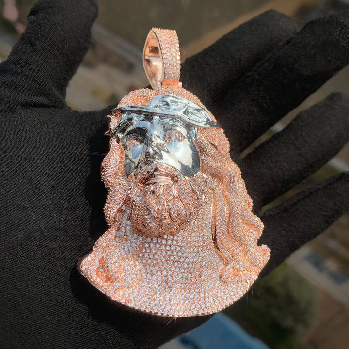 Rose-gold-tone and silver-tone Jesus portrait pendant against a black glove