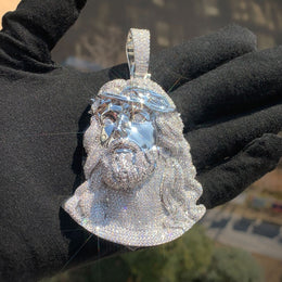 Silver-tone Jesus portrait pendant held against a black glove