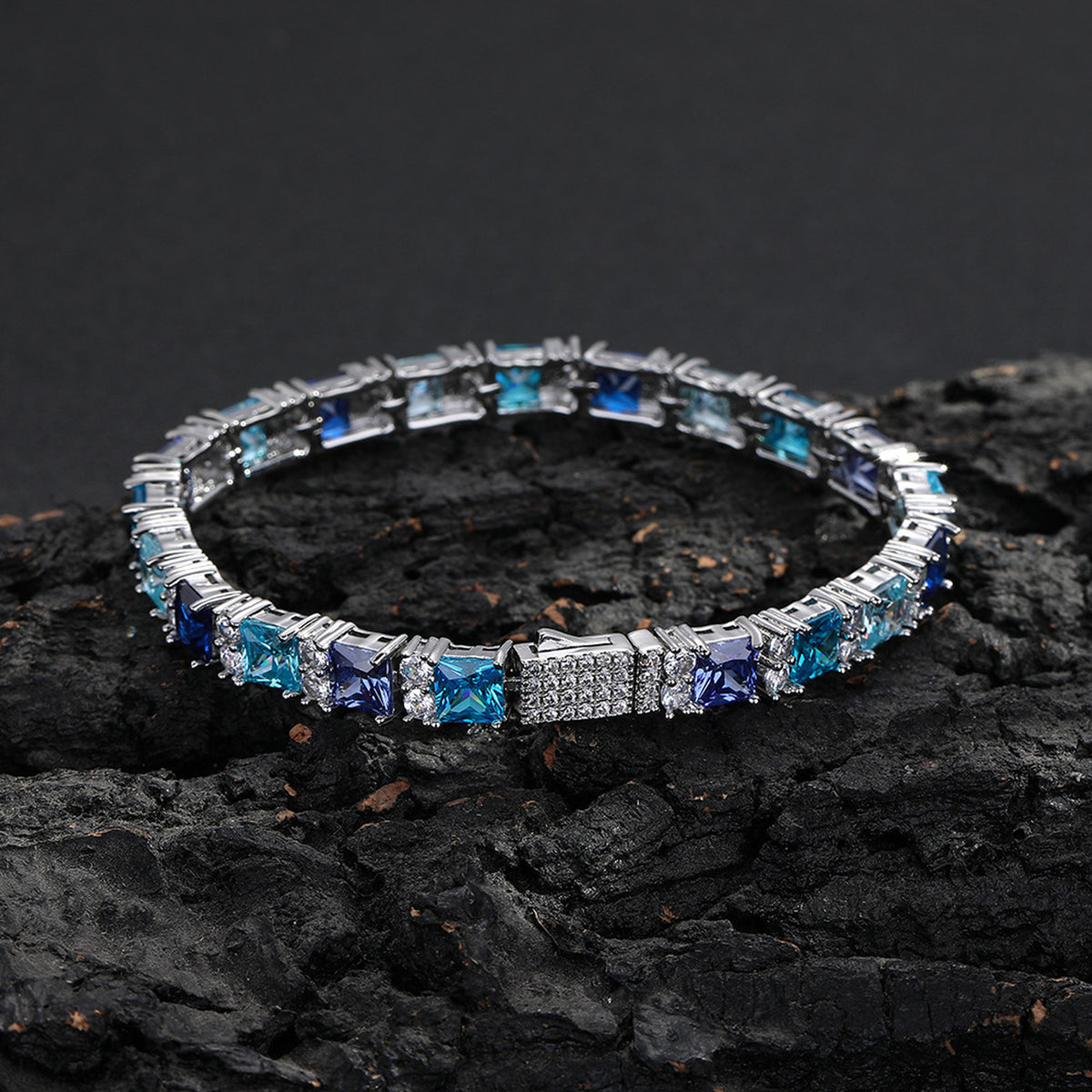 Multicolor square-cut tennis bracelet displayed on dark rock