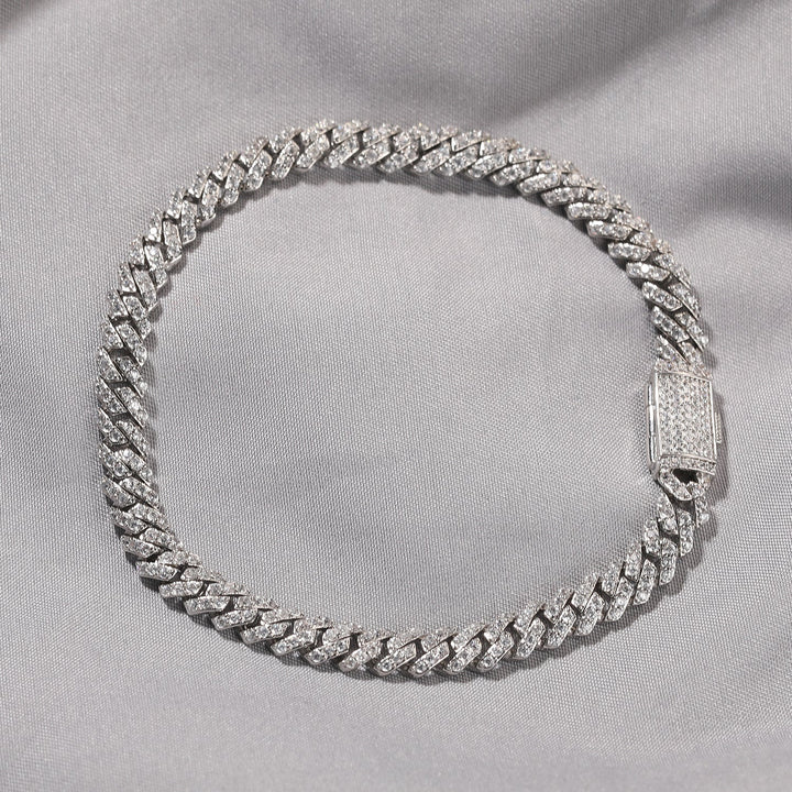 Silver-tone stone-set Cuban link bracelet arranged on pale fabric