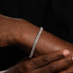 Silver-tone 6mm iced Cuban bracelet on wrist with logo-free black background