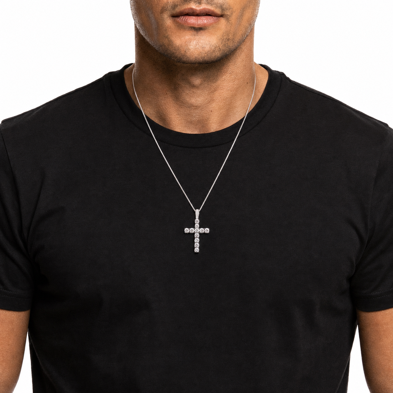 A man wearing a silver cross pendant necklace with clear stones, shown against a plain white background.