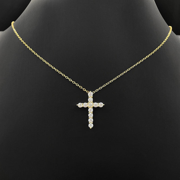 Gold-tone stone-set cross pendant on a fine chain displayed on a black bust