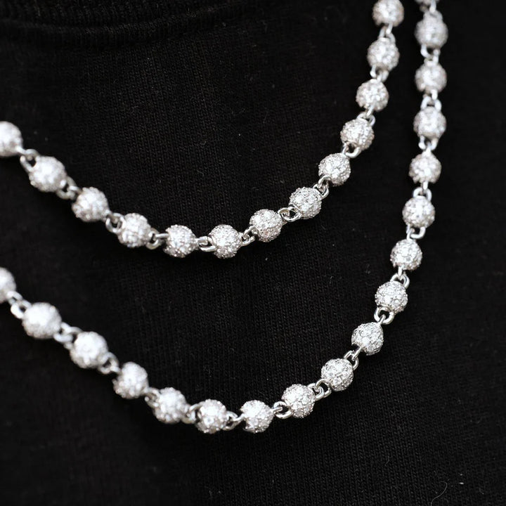Two silver-tone stone-set bead necklaces on a black display