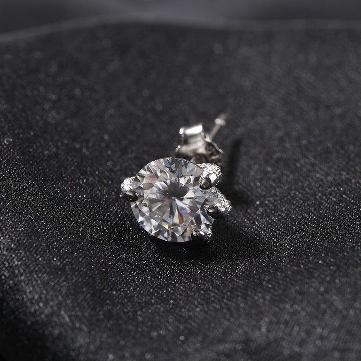 Round clear-stone stud earring on dark fabric