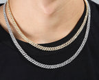 Two iced out Cuban link chains, one gold and one silver, worn over black shirt - Miles Jewellery