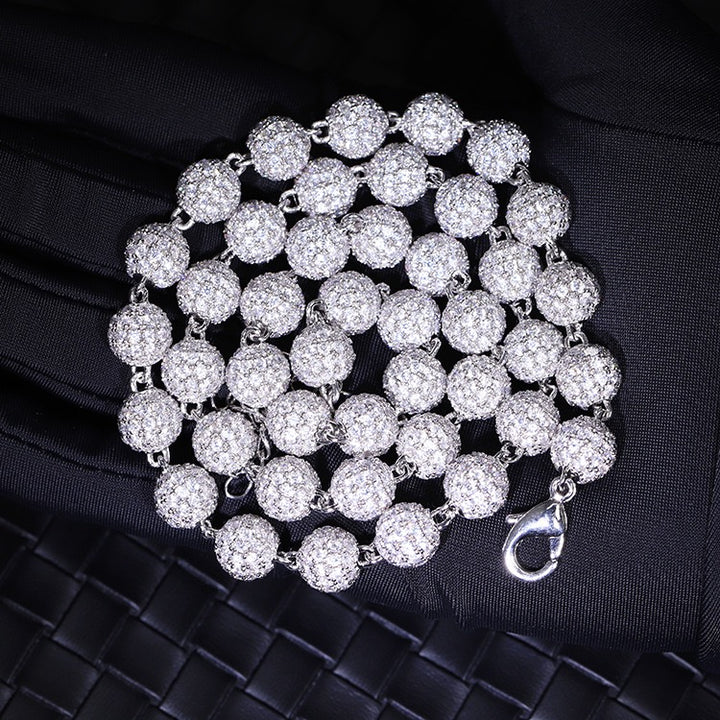 Silver-tone stone-set bead necklace coiled on a dark surface