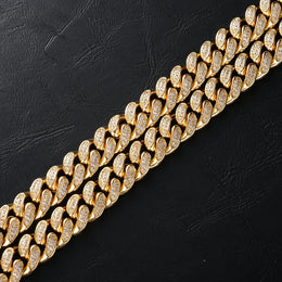 Gold Cuban link chains with diamond accents on black leather background - Miles Jewellery