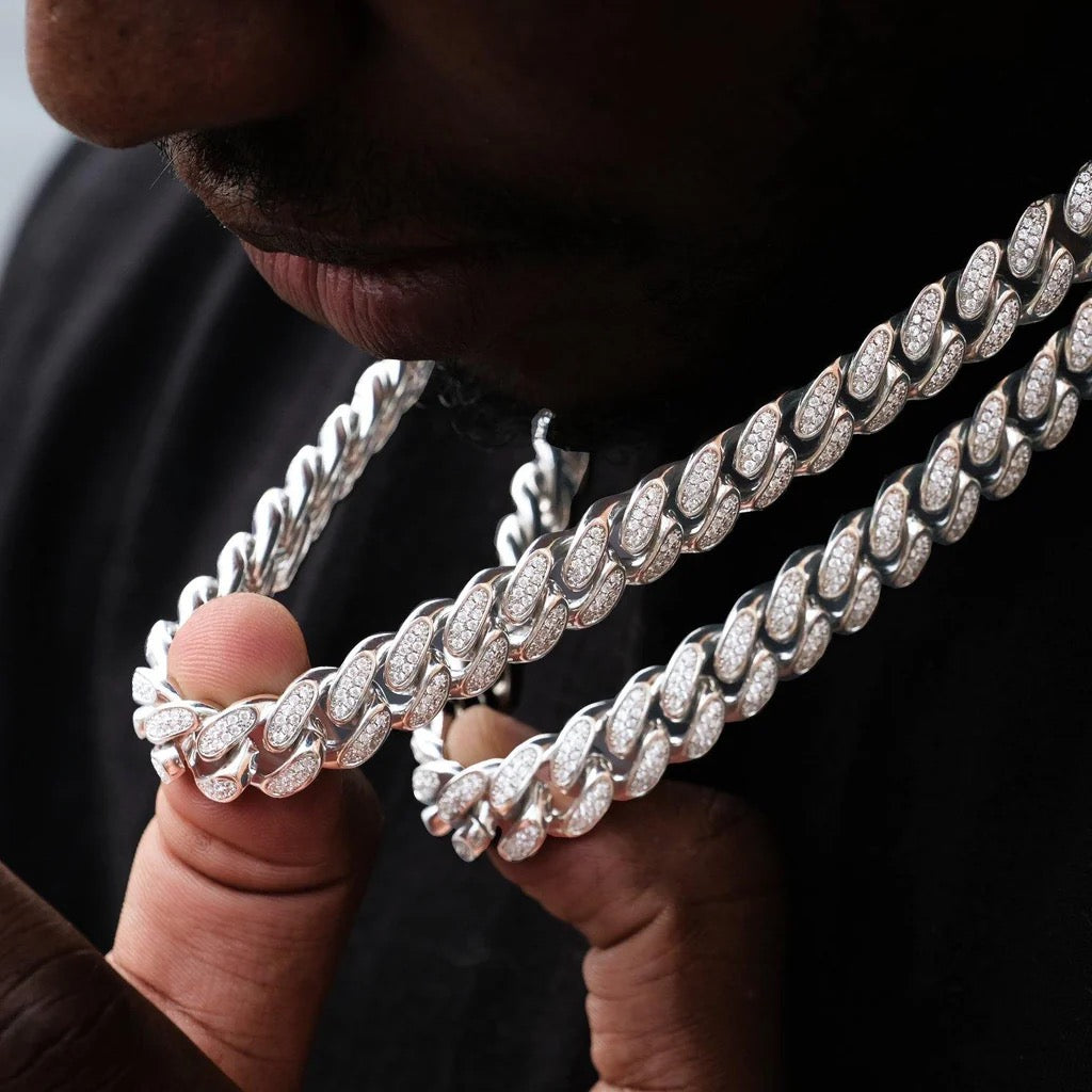 Close-up of man holding iced out Cuban link chains, hip hop jewelry style - Miles Jewellery