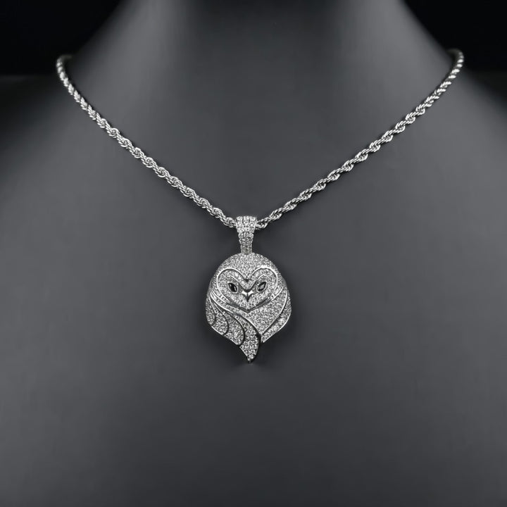Silver-tone small owl pendant on a chain over a black bust