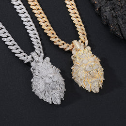 Two lion head pendants on chains against a black background