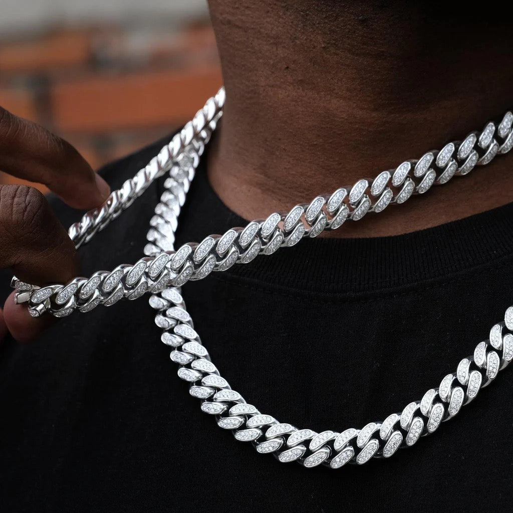 Close-up of two iced out Cuban link chains with diamonds on black shirt - Miles Jewellery