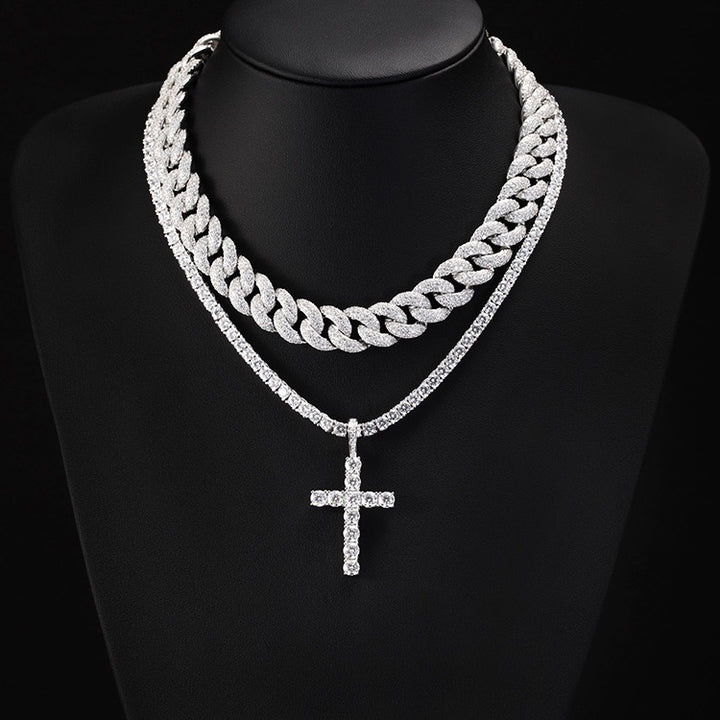 Cross pendant on a fine chain layered with a Cuban link chain on a display bust