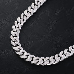 Close-up of iced out Cuban link chain necklace on black leather background - Miles Jewellery