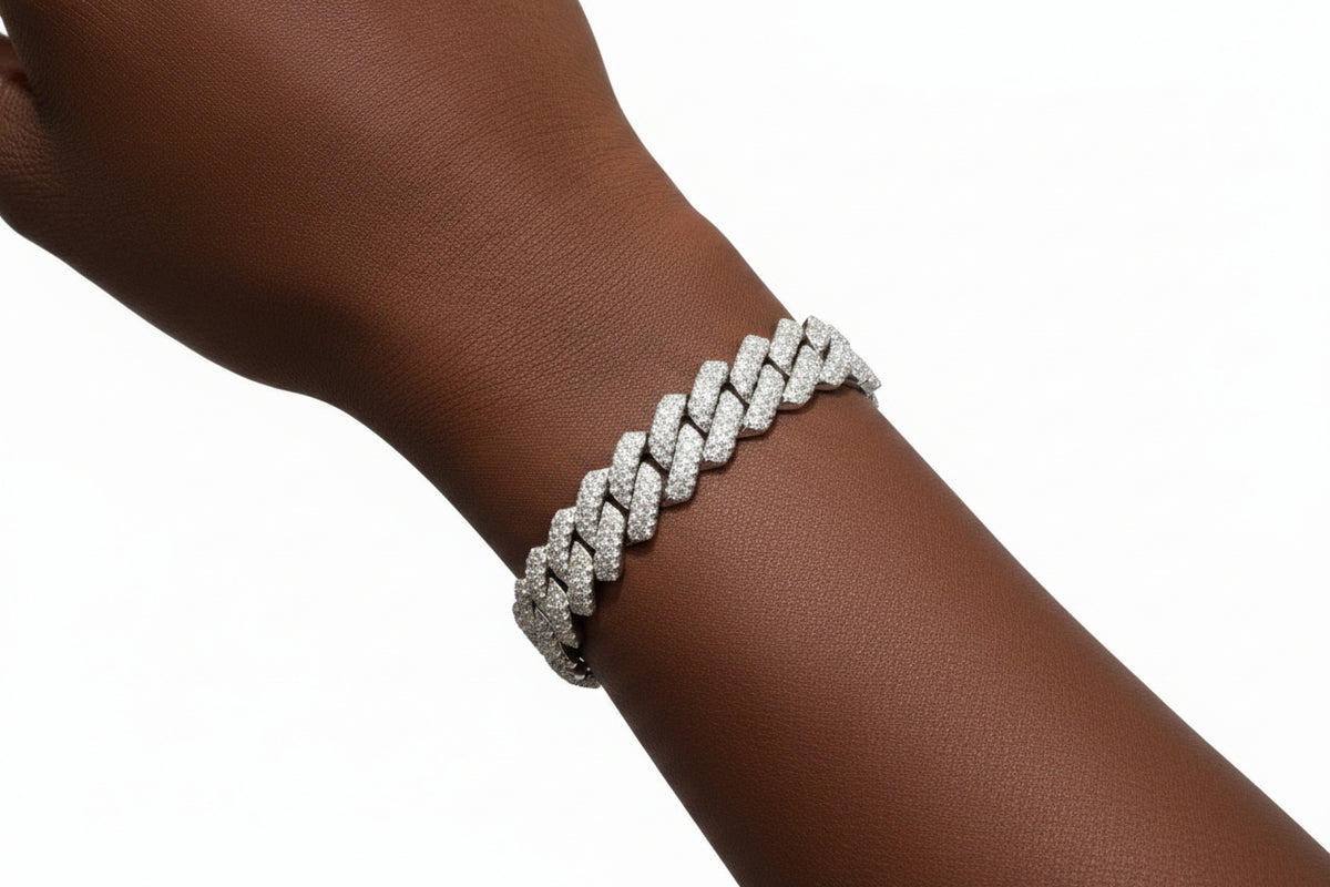 A close-up of a silver-toned braided chain bracelet with pavé-set clear stones worn on a person's wrist against a black shirt background.