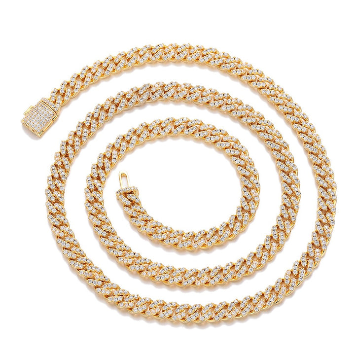 Gold-tone stone-set Cuban link necklace arranged in a spiral on white