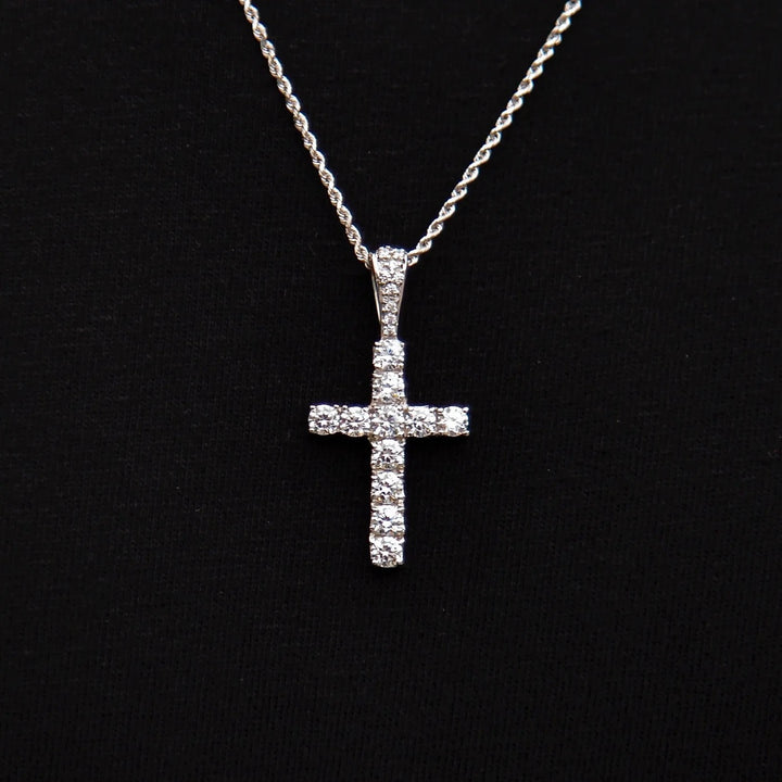 Silver-tone stone-set cross pendant on a fine chain against black