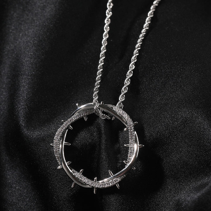 Silver-tone circular thorn pendant on dark fabric