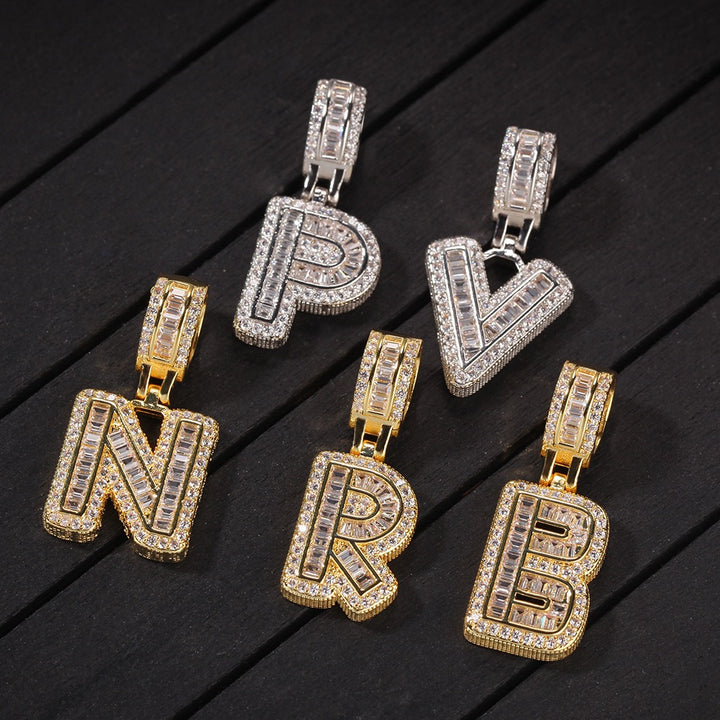 Gold-tone and silver-tone initial pendants arranged on dark wooden boards