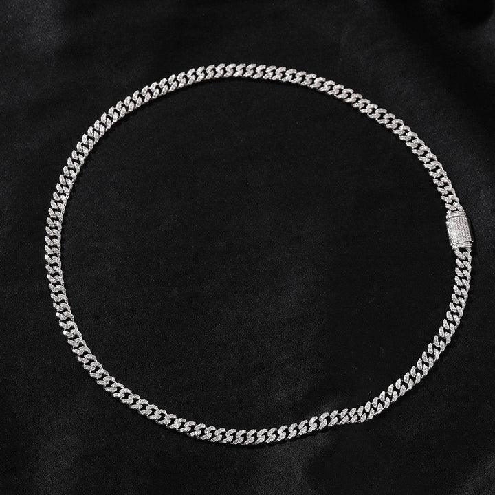 Silver-tone stone-set Cuban link necklace arranged in a circle on black