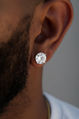 Close-up of a diamond earring on an ear with a dark background