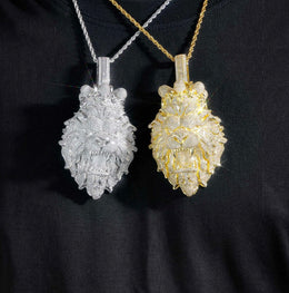 Two ornate pendants, one silver and one gold, on a black background.