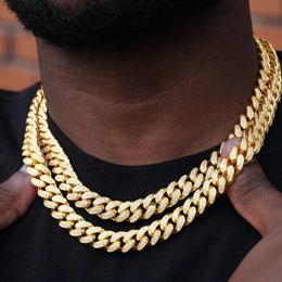 Close up of gold Cuban link chains with diamond accents on a man's neck - Miles Jewellery