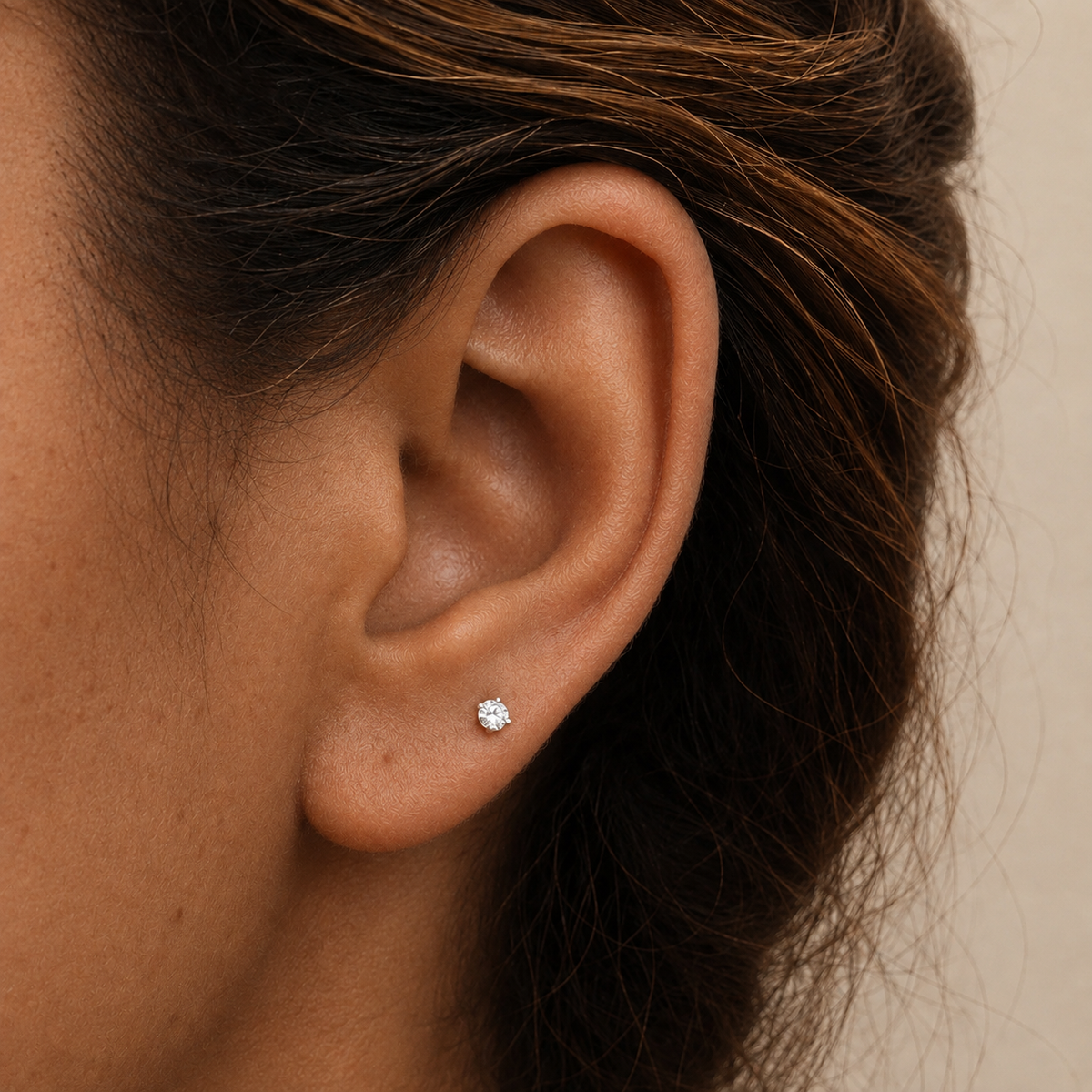 A close-up of a person's ear wearing a small 3mm round stud earring