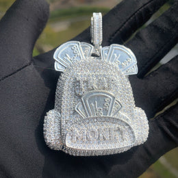 Silver-tone backpack pendant with banknote motifs held on a black glove