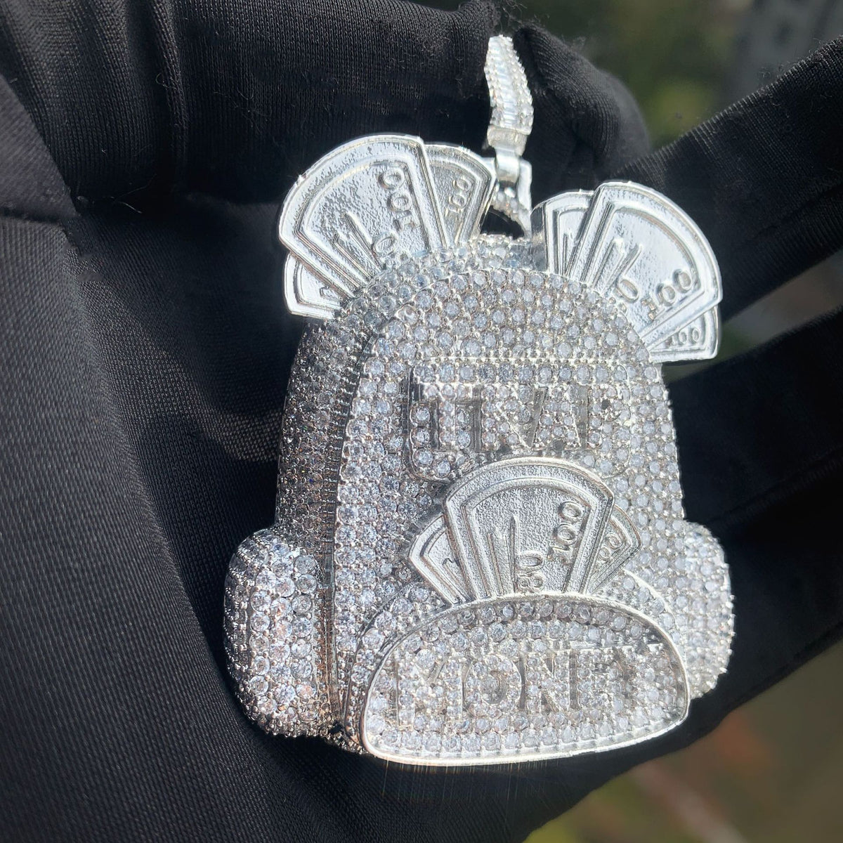 Close front view of the silver-tone backpack pendant and raised pocket detail