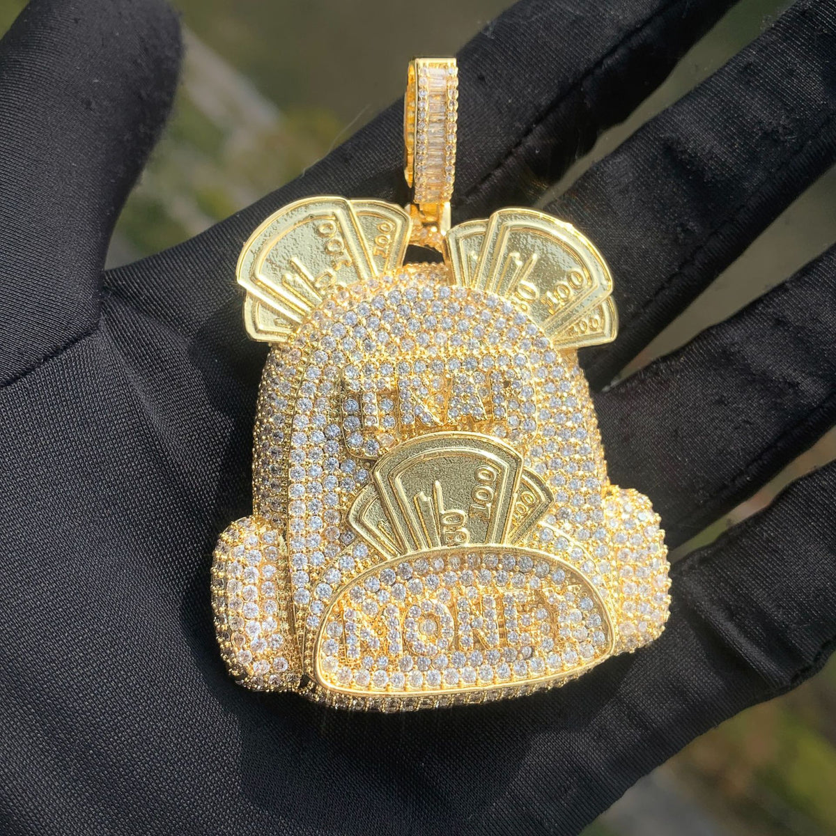 Gold-tone backpack pendant with stone-set pockets and banknote motifs