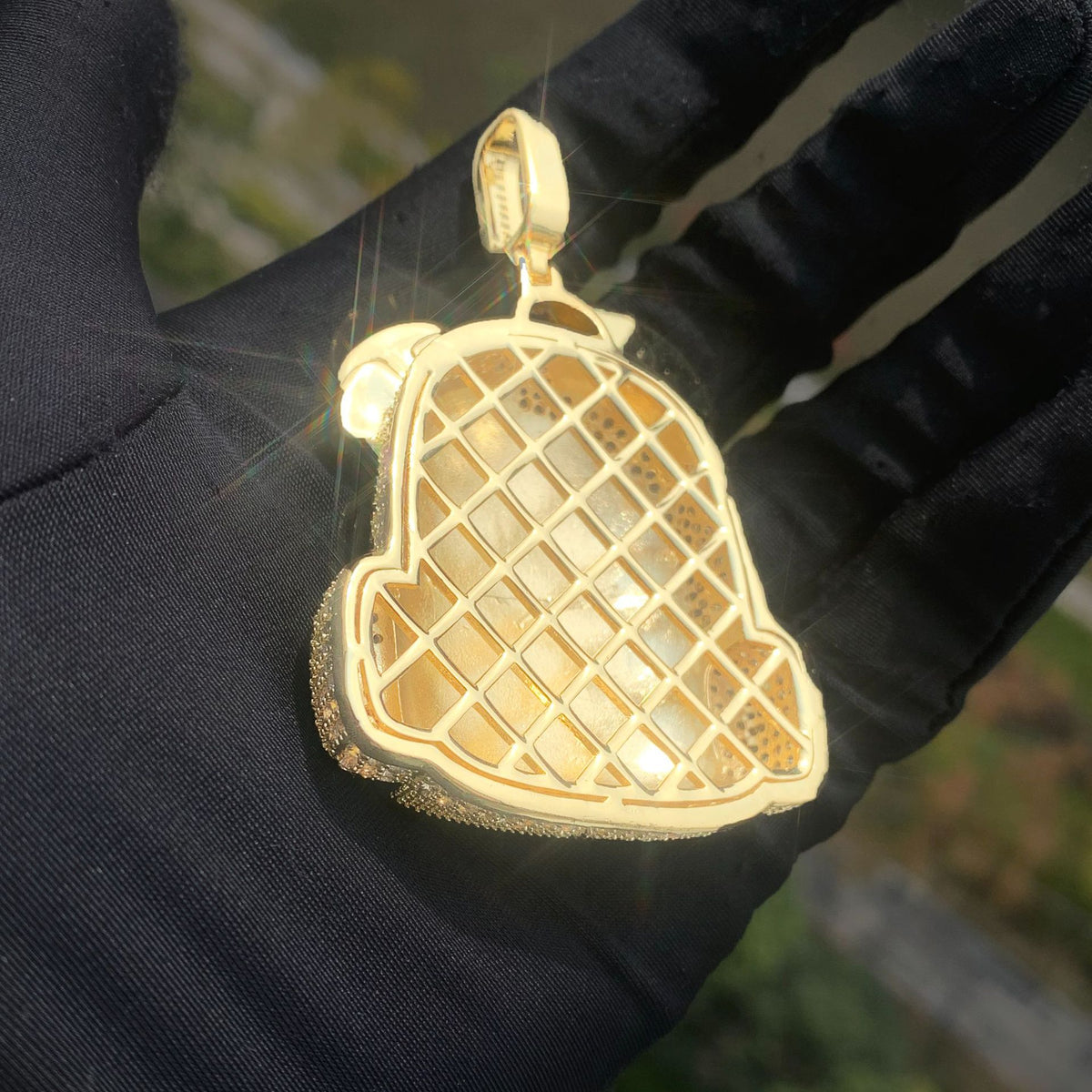 Back of the gold-tone backpack pendant showing an open lattice structure
