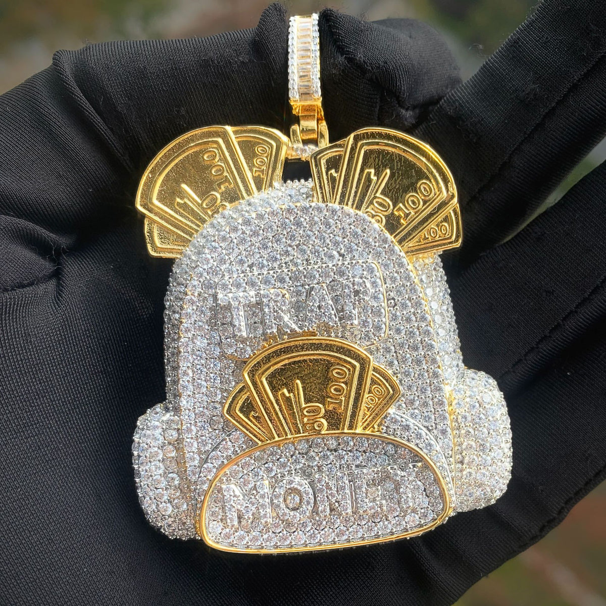 Front view of the two-tone backpack pendant held on a black glove