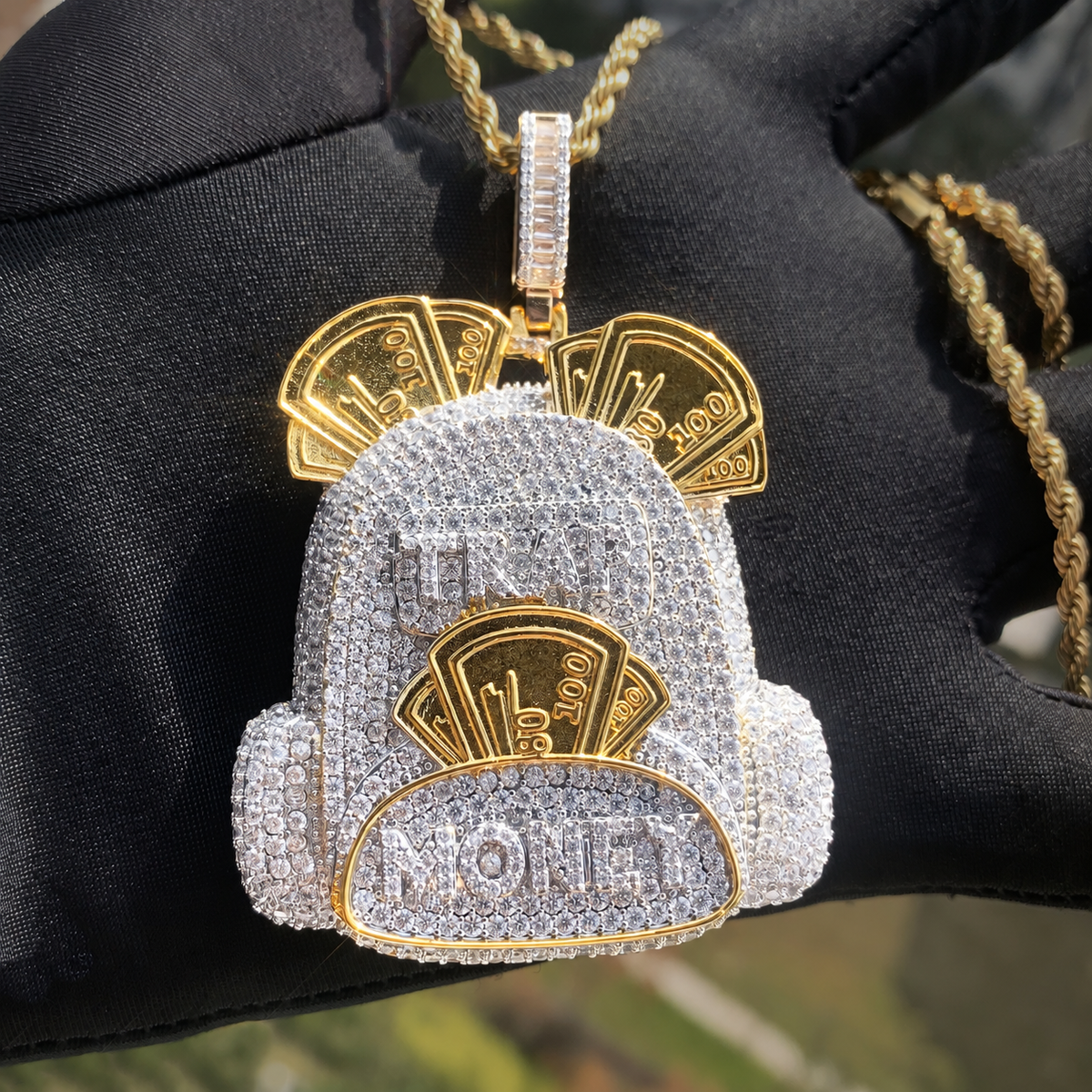 Two-tone backpack pendant with raised banknote details resting on a black glove