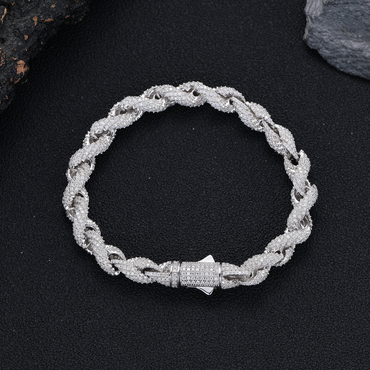 Rope bracelet arranged in a circle on a dark surface with its clasp closed