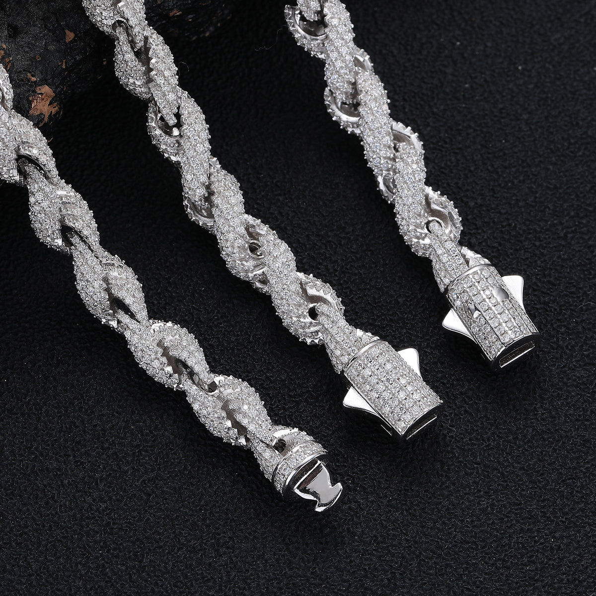 Rope links and open box clasp connections with side safety catches on a dark surface