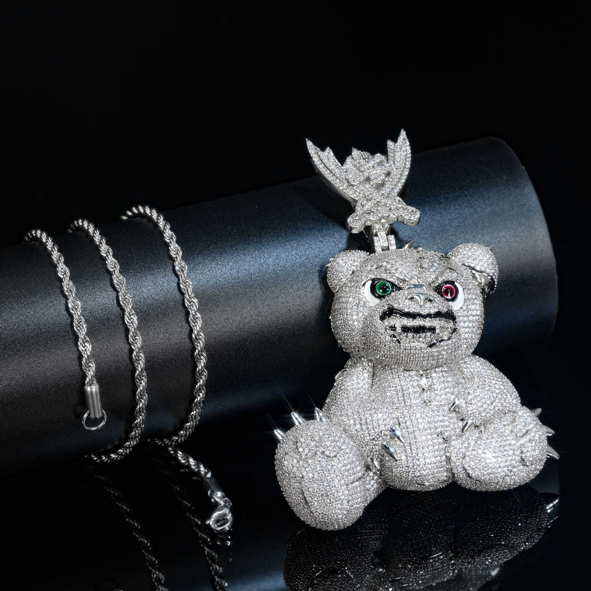 Silver-tone bear pendant beside a black cylindrical display