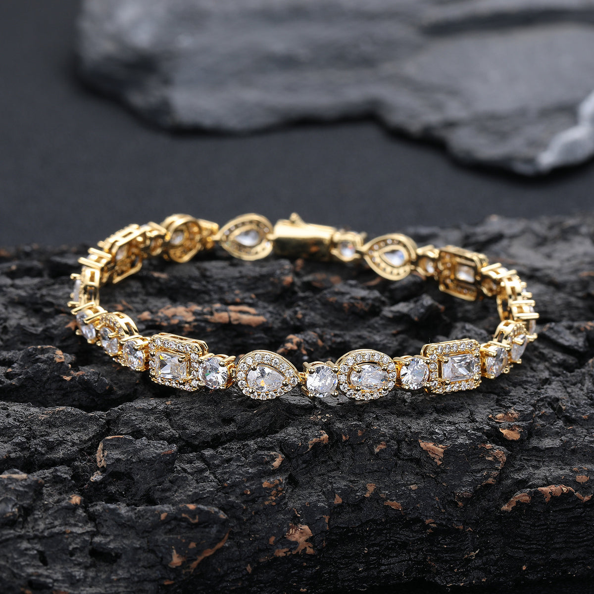 Gold-tone geometric halo bracelet resting on dark stone