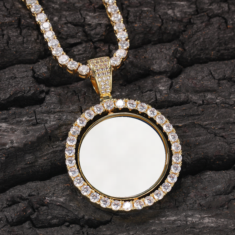 Gold-tone photo pendant with a white photo area resting on dark textured wood