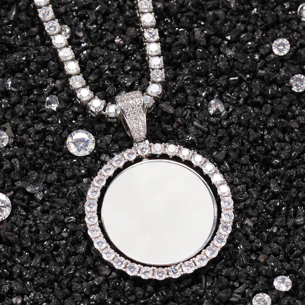 Silver-tone photo pendant with a white photo area on dark gravel beside loose faceted stones